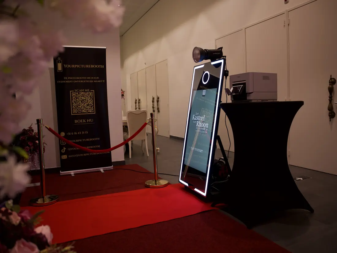 Photobooth met bloesemdecoratie en rode loper op een bruiloft