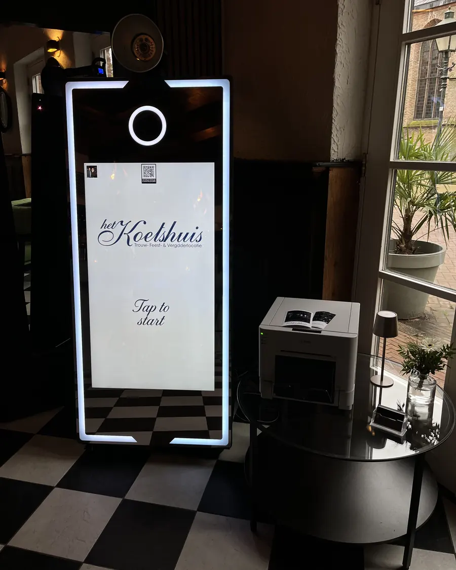 Een complete spiegel photobooth bestaat uit een manshoge spiegel met camera en flitser, een printer op een bijzettafel en de bekabeling, hier bij Het Koetshuis.
