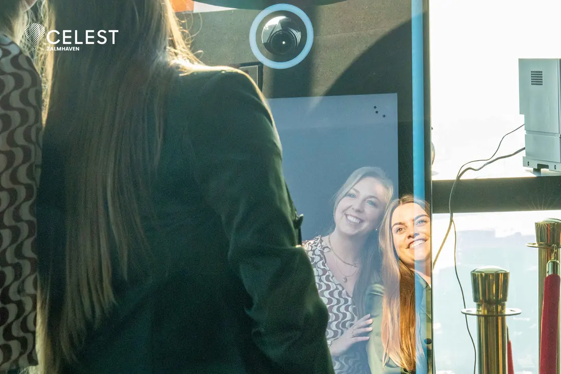 Gasten lachen naar zichzelf in de spiegel van de photobooth