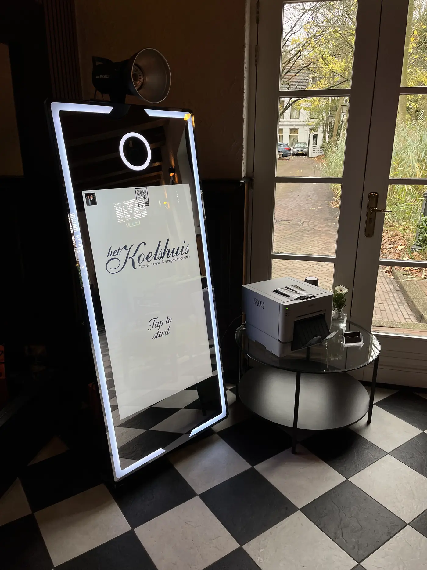 Mirror-photobooth met gepersonaliseerd startscherm, opgesteld naast de printer op een eventlocatie