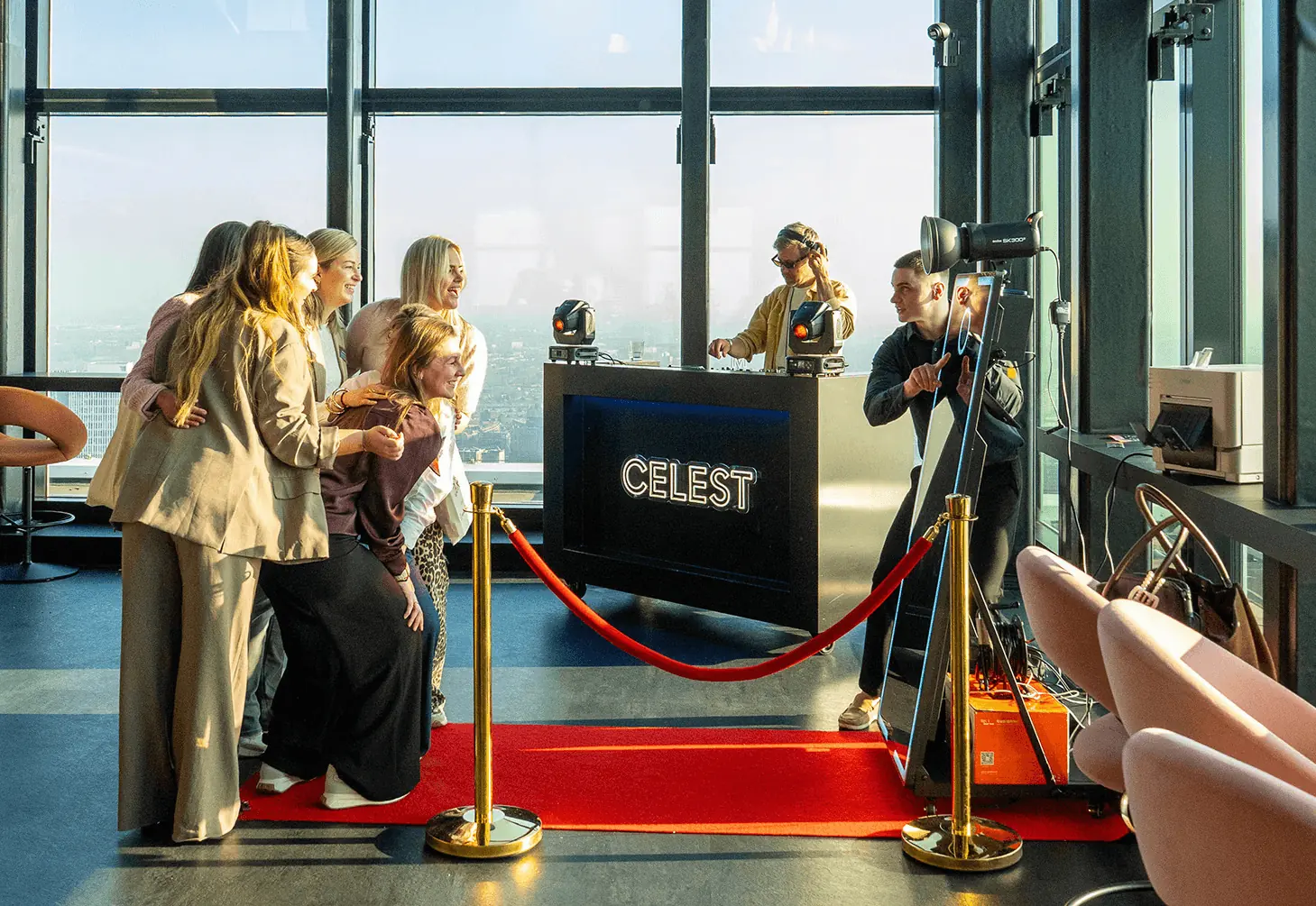 Gasten poseren bij de photobooth op de rode loper tijdens een zakelijk event met uitzicht over de stad