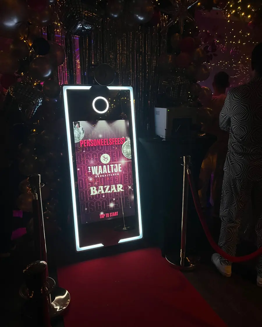 Spiegel photobooth met disco-startscherm op het personeelsfeest van t Waaltje, met rode loper en gouden afzetpalen