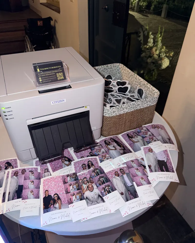 Stapel geprinte fotostrips naast de printer